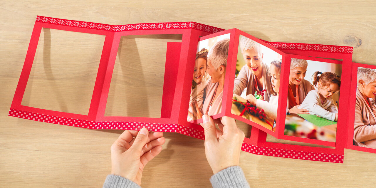 Hände halten ein offenes Fotobuch mit bunten Erinnerungen.