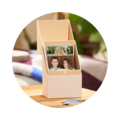 Eine offene Geschenkbox mit Fotos von zwei Personen im Inneren, ideal für schöne Erinnerungen.