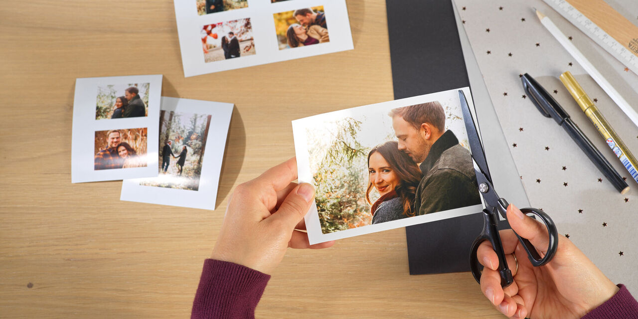 Eine Person schneidet ein Foto mit einer Schere und hält das Bild in der anderen Hand, um es kreativ zu gestalten
