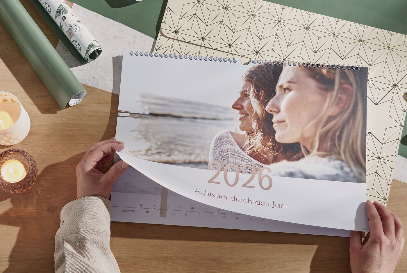 Ein Mensch blättert durch einen Fotokalender für das Jahr 2026.